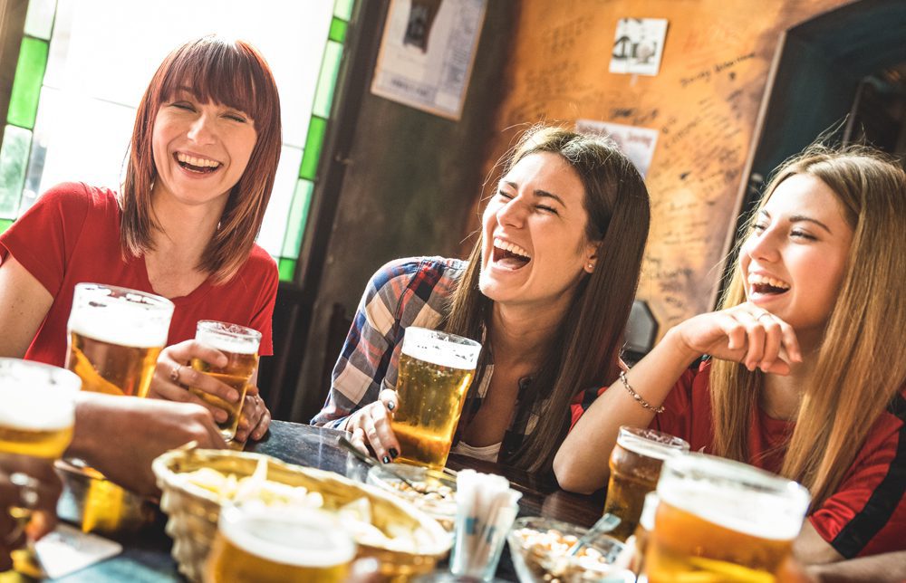 Happy girlfriends women group drinking beer at brewery bar restaurant - Friendship concept with young female friends enjoying time and having genuine fun at cool vintage pub - Focus on left girl